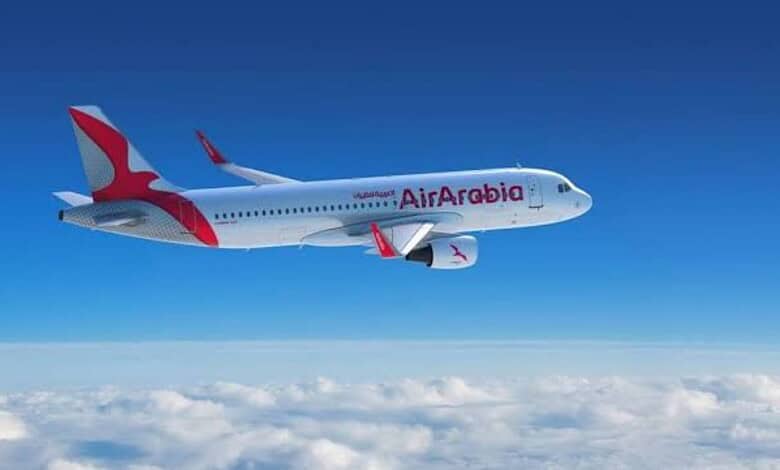 Air Arabia passenger aircraft flying above clouds.