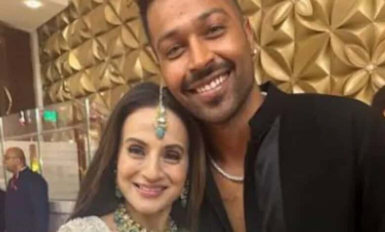 Ameesha Patel and Hardik Pandya smiling at an event, with a decorative gold background.