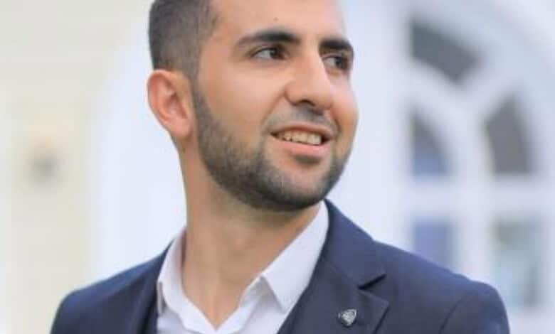 Confident young man in a suit smiling outdoors, representing professionalism and success.