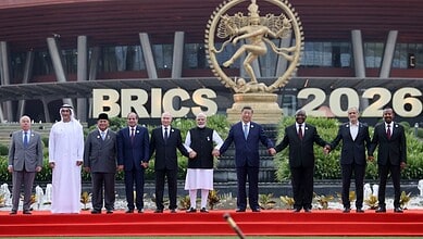 BRICS leaders standing together at the 2026 summit in front of a large Ganesha statue and BRICS 2026 sign.