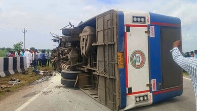 Bus overturned on roadside after accident near Kamareddy, with onlookers at the scene.