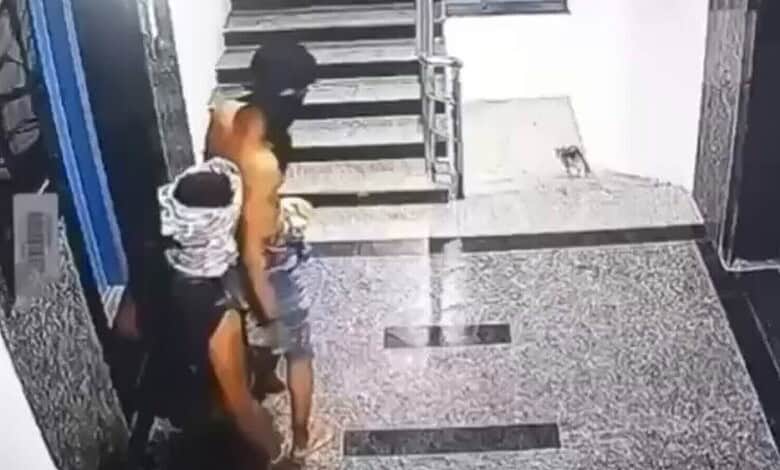 Two men with covered faces entering a building through a glass door.