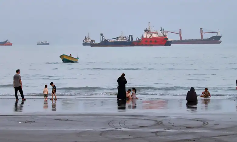 Large oil tanker sailing through the Strait of Hormuz with smaller boats nearby.