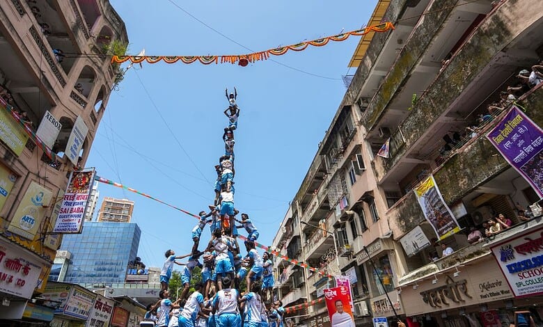 People forming a human pyramid in a busy urban street during a festival in Hyderabad.