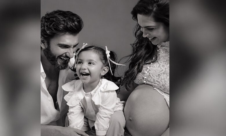 Happy family with a pregnant woman, a man, and a young girl smiling together.