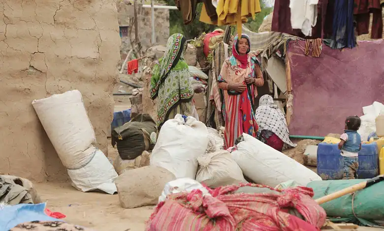 Yemeni refugees in a crowded camp with bags, children, and makeshift shelters.