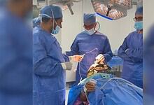Surgeons in blue scrubs and masks operate on a patient during Parkinson's treatment.
