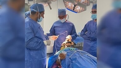 Surgeons in blue scrubs and masks operate on a patient during Parkinson's treatment.