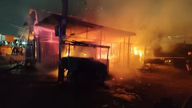 Nighttime fire at a building with flames and smoke, emergency response needed.