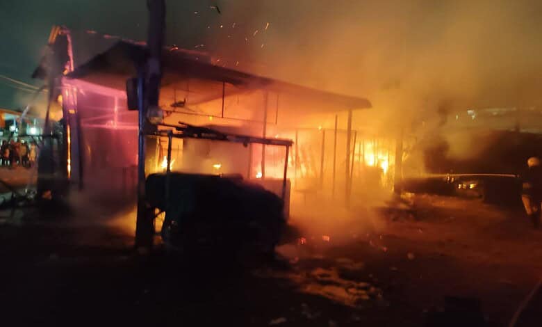 Nighttime fire at a building with flames and smoke, emergency response needed.