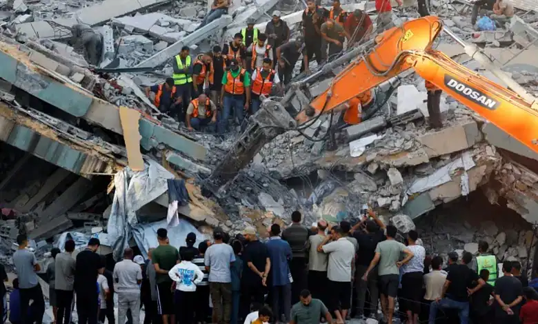 Rescue workers and onlookers at the site of a building collapse in Gaza, with heavy machinery and debris.