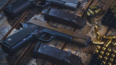 Handgun, magazines, and ammunition displayed on a wooden surface.