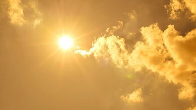 Bright sun shining through partly cloudy sky during a warm day in Telangana.