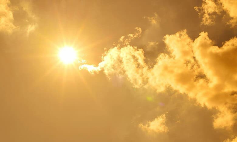Bright sun shining through partly cloudy sky during a warm day in Telangana.