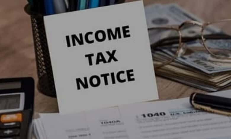 Income tax notice document with calculator, money and glasses on a desk.