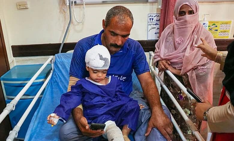 Child in hospital bed with bandaged head, surrounded by family members and medical staff.