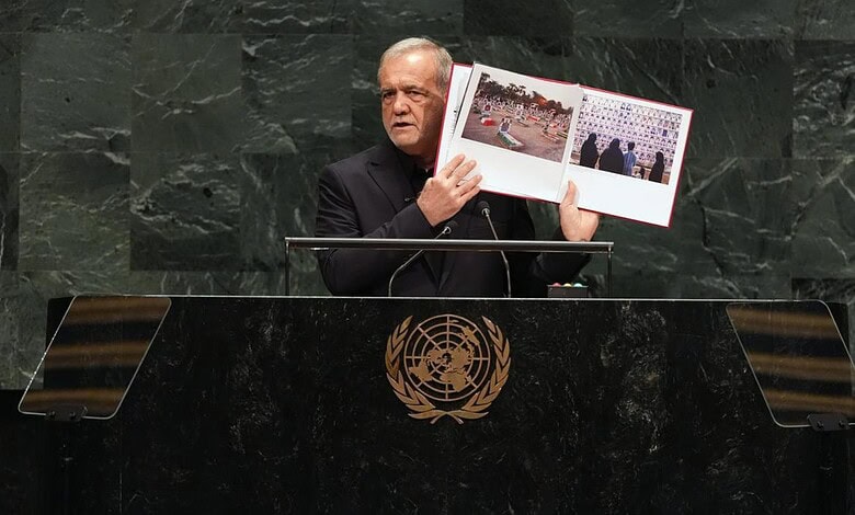 Iran president holding a photo album at UN General Assembly podium.