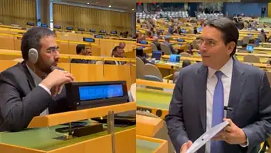 Israeli envoy and Iranian diplomat at UN meeting, engaging in discussion.