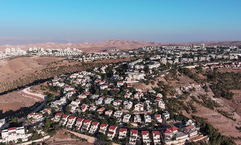 Aerial view of Israeli settlements in the West Bank with surrounding hills and mountains.
