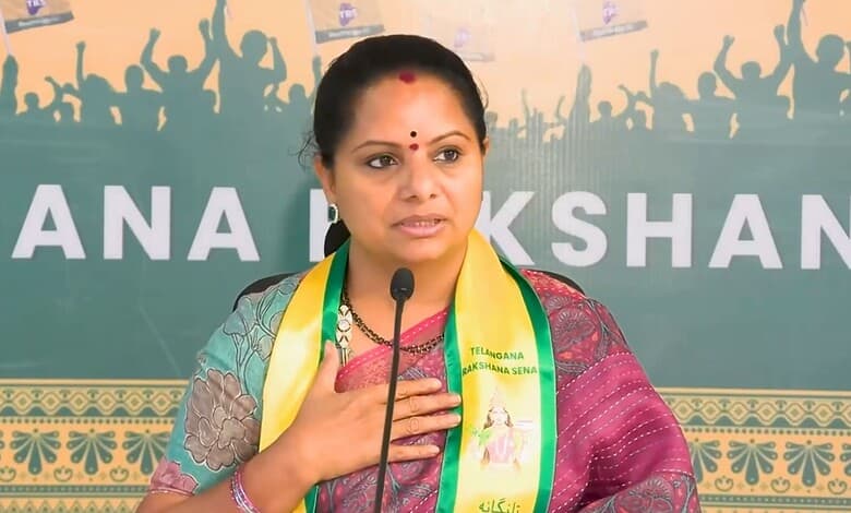Kavitha speaking at a political event with a backdrop of supporters and banners.