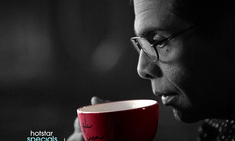 Karan Johar with glasses holding a red coffee mug in black and white image.