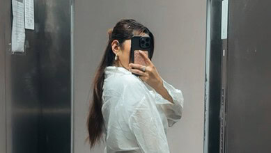 Woman taking a mirror selfie with a smartphone in an elevator.