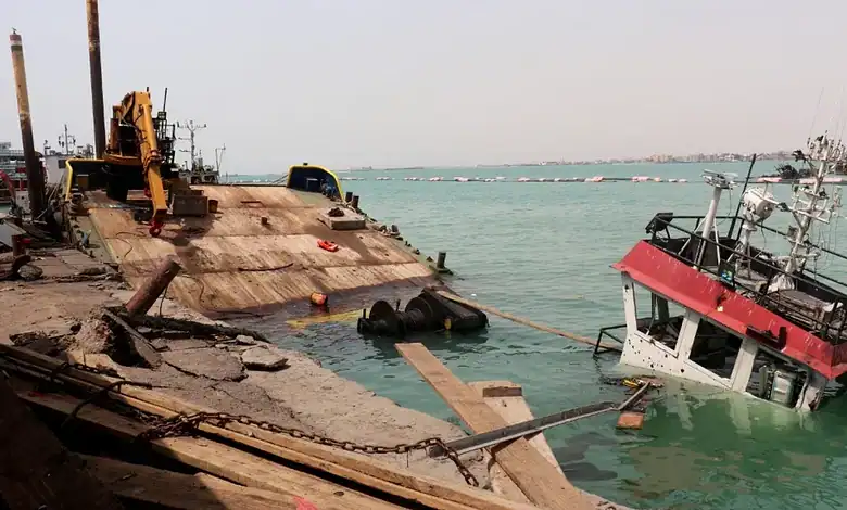 Damaged ship partially submerged near the Yemeni coast with rescue equipment nearby.