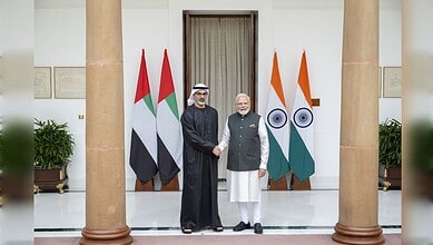 Modi and Sheikh Khaled shake hands at BRICS Summit with India and UAE flags behind them.