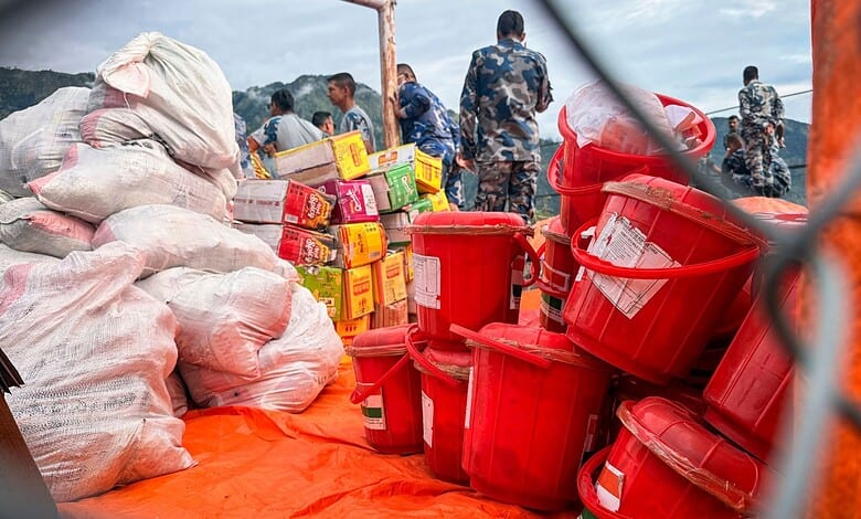 Relief workers prepare supplies including buckets and food packages amid flood response in Nepal.