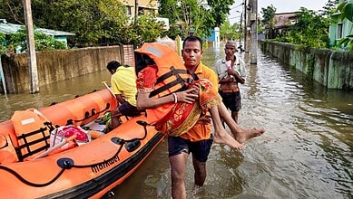 An official rescues flood-affected residents and moves them to a safer place following heavy rainfall, at Sahadevkhunta, in Baleswar district, Odisha, Saturday, Sept. 26, 2026. (PTI Photo)