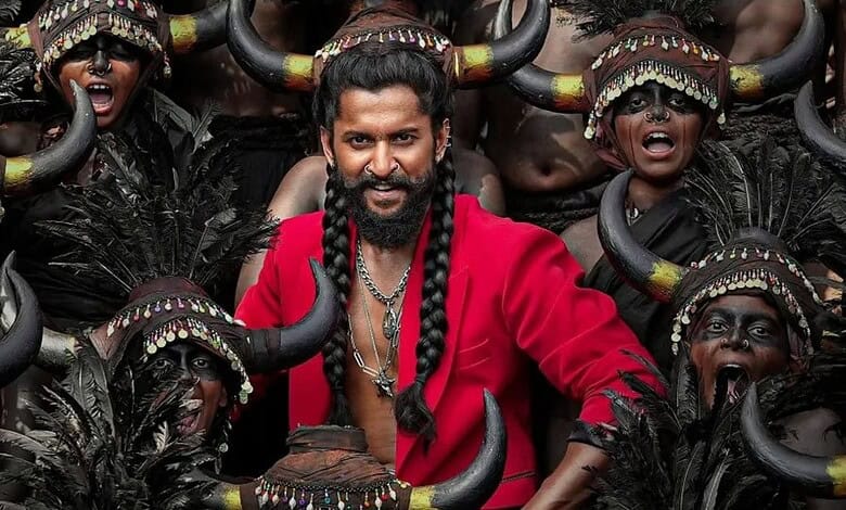 Man in red shirt performing tribal dance with dancers wearing horns and traditional attire.