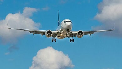 Passenger airplane approaching for landing with extended landing gear and open flaps.