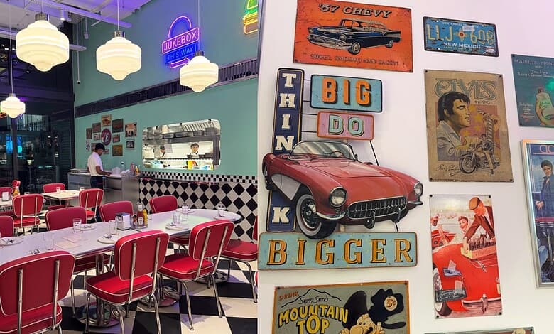Retro-themed diner interior with vintage car and 1960s posters, vibrant neon lights, and red chairs.