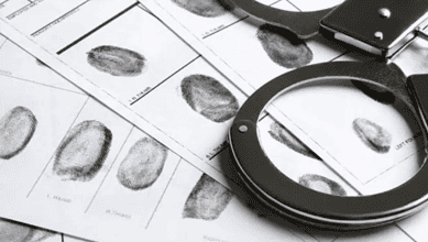 Fingerprint analysis with magnifying glass and police documents for forensic investigation.