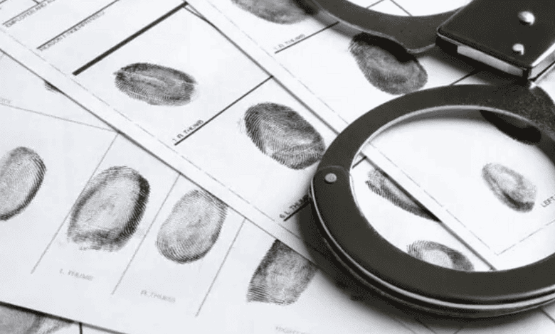 Fingerprint analysis with magnifying glass and police documents for forensic investigation.