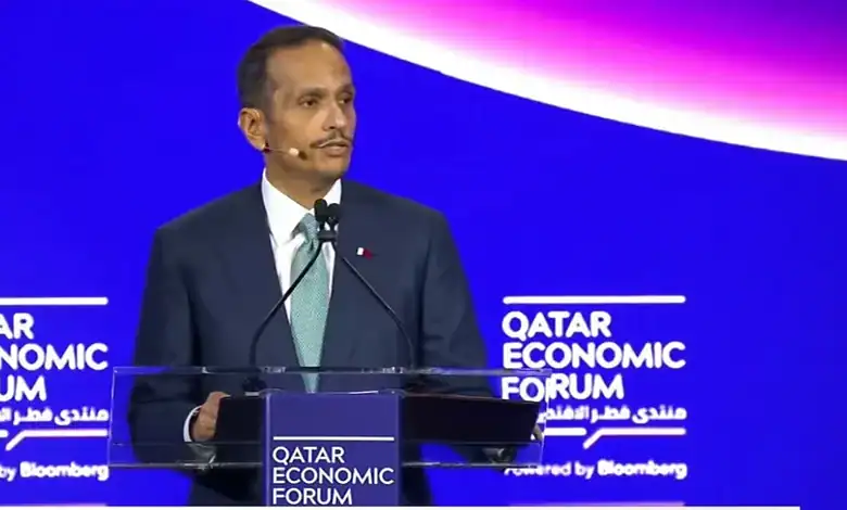 Qatar Prime Minister speaking at the Qatar Economic Forum with a blue background and event branding.