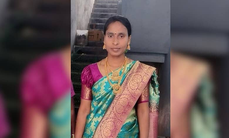 Indian woman wearing a colourful saree with gold jewellery, standing outdoors.