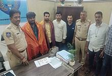 Group of men, including police officers, standing around a table with gold and cash in Hyderabad.
