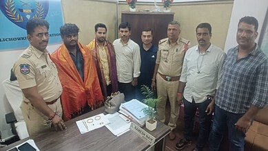 Group of men, including police officers, standing around a table with gold and cash in Hyderabad.