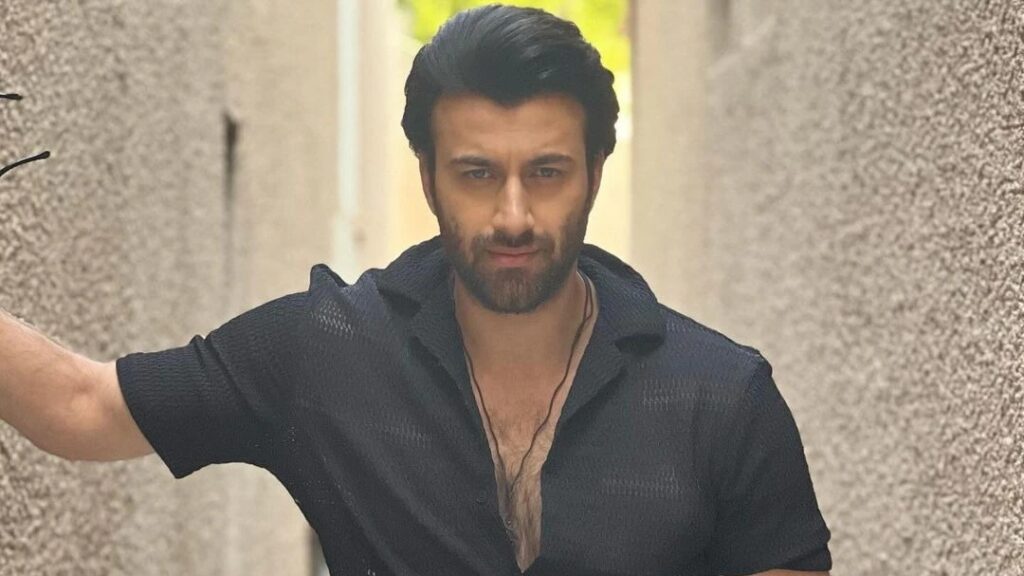 Portrait of a male contestant from Bigg Boss 20 in a black shirt in a narrow corridor.