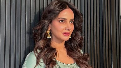 Saba Qamar with wavy hair and traditional earrings, looking to the side.