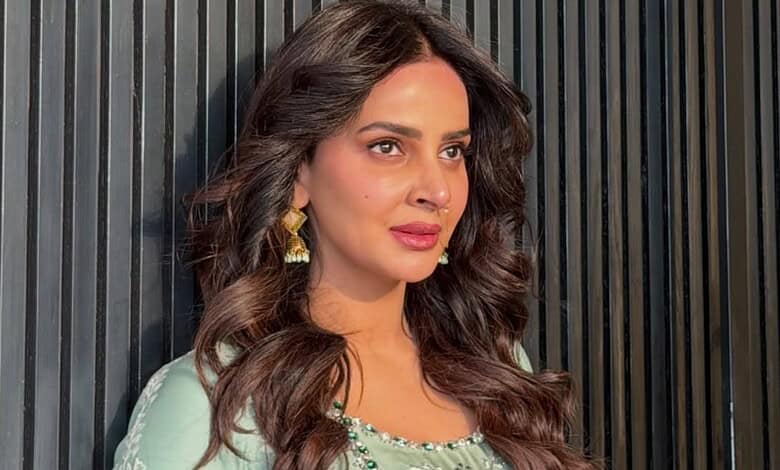 Saba Qamar with wavy hair and traditional earrings, looking to the side.