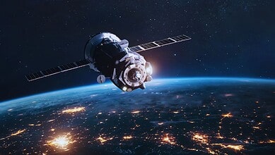 Satellite orbiting Earth with city lights visible on the surface at night.