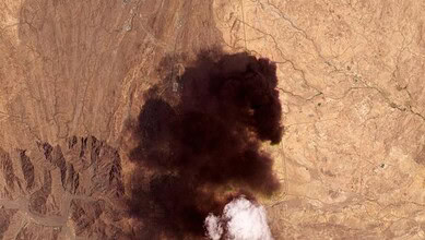Large black smoke plume rising from a desert landscape after Houthi attack on Saudi Arabia.