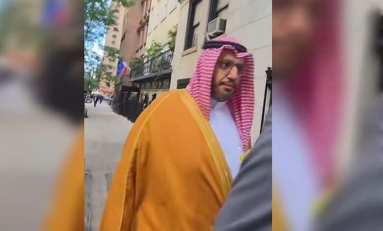 Palestinian American in traditional attire confronts Saudi official outside building.