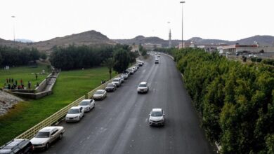 Cars driving on a road lined with trees and greenery in Saudi Arabia.