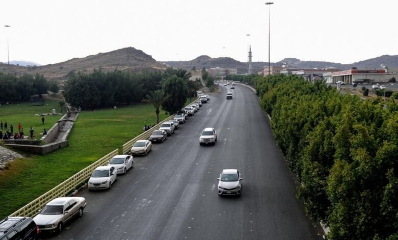Cars driving on a road lined with trees and greenery in Saudi Arabia.