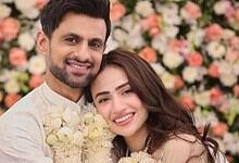 Shoaib Malik and his wife smiling at their wedding celebration with floral backdrop.