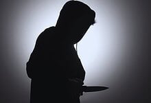 Silhouette of a person holding a knife in a dark setting, creating a mysterious and ominous atmosphere.