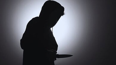 Silhouette of a person holding a knife in a dark setting, creating a mysterious and ominous atmosphere.